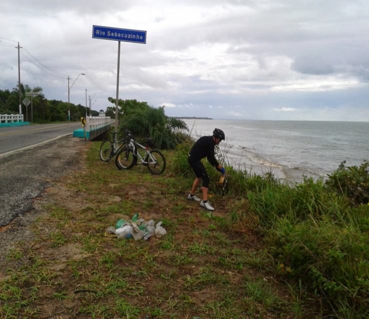 Pesquisador retirando resíduos sólidos na desembocadura do Rio Sabacuzinho com a praia. 