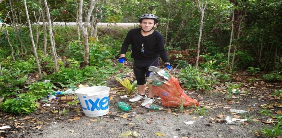 Pesquisador recolhendo resíduos sólidos. Ponto frequentado por pessoas que estacionam o carro na rodovia e acampam no local, com vistas à diversão e banho na praia, deixando resíduos para trás, em qualquer lugar, mesmo com essa espécie de lixeira encontrada no local. 